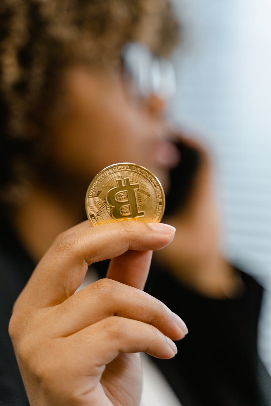 person holding gold round coin